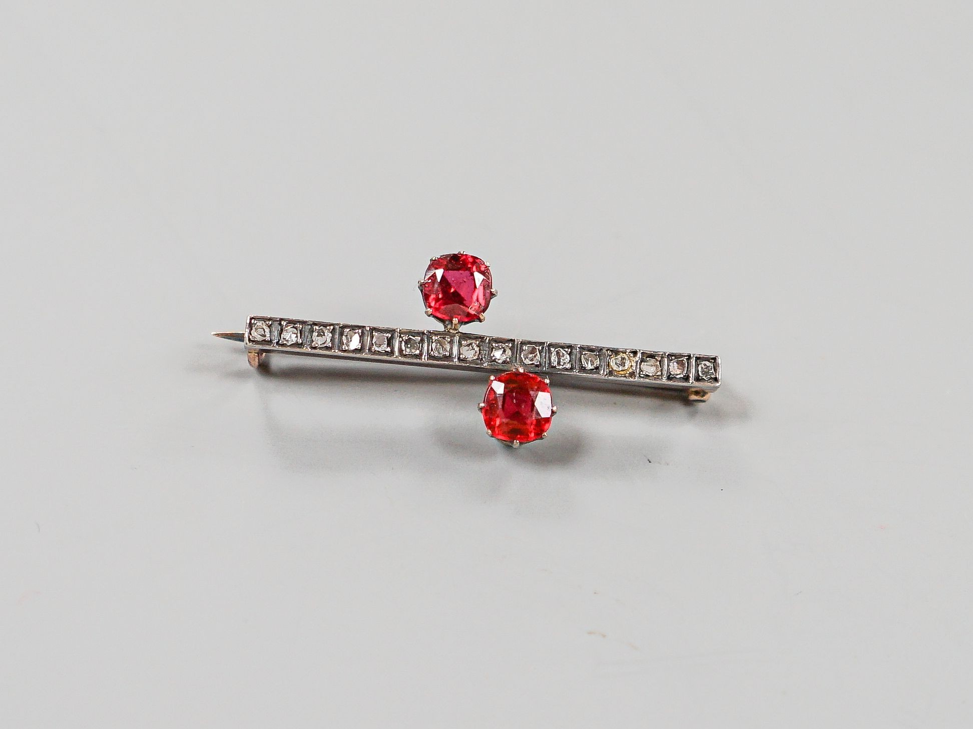 A yellow metal, rose cut diamond chip and two stone red doublet set bar brooch, 36mm, gross weight 3.7 grams.